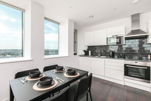A modern kitchen with a dining area, large windows, and a view of the city.