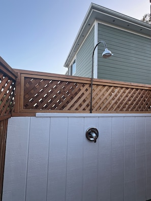 A white exterior wall with a metal door and a wooden lattice fence. - 5 minutes to the beach! The Hideaway on Lillie Ave. (Summerland)