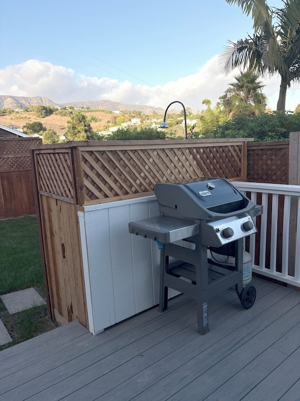 A barbecue grill on a wooden deck with a white fence and a view of a hilly landscape. - 5 minutes to the beach! The Hideaway on Lillie Ave. (Summerland)
