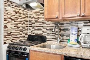 A kitchen with a modern design, featuring a patterned backsplash, stainless steel appliances, and wooden cabinets. - Tideview Retreat with Indoor and Outdoor Pools (Myrtle Beach)