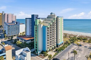 A multi-story hotel with a central courtyard, located near a beach with a clear view of the ocean. - Tideview Retreat with Indoor and Outdoor Pools (Myrtle Beach)