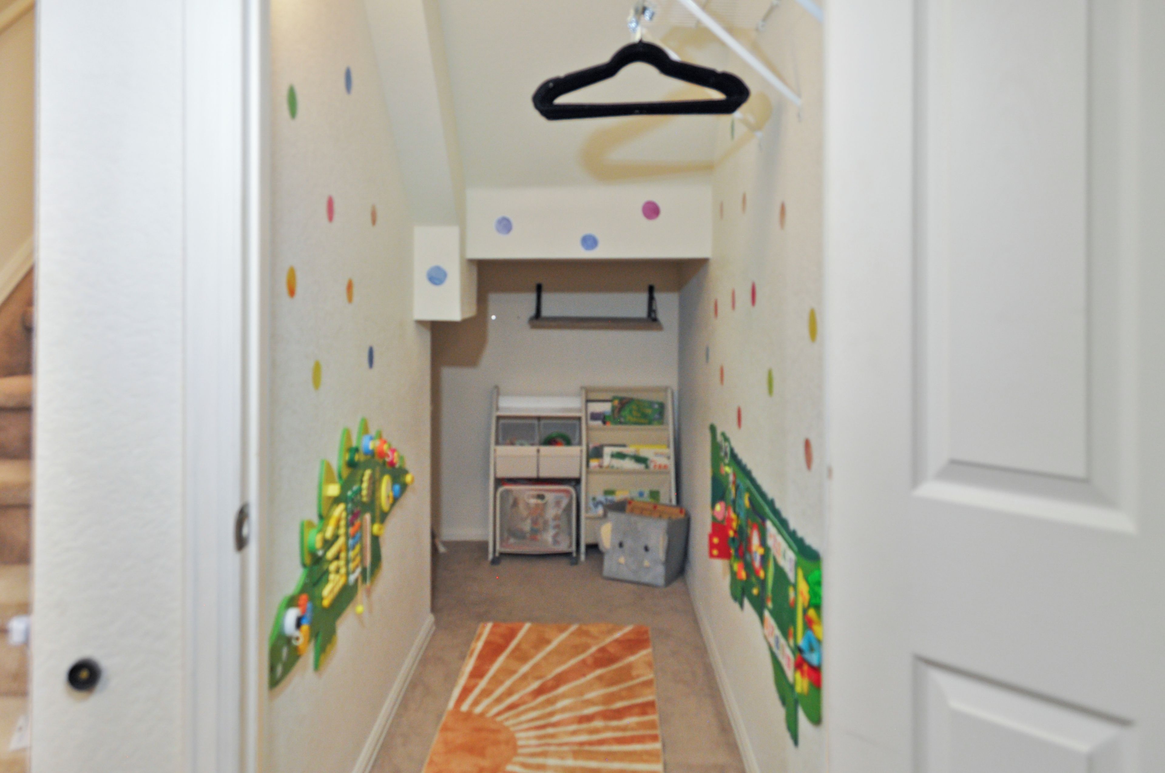 Un couloir avec une étagère à jouets, une petite table et un tapis.