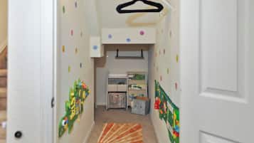 Un couloir avec une étagère à jouets, une petite table et un tapis.