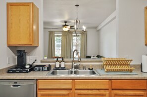 A kitchen with wooden cabinets, a coffee bar, a sink, and a ceiling fan.