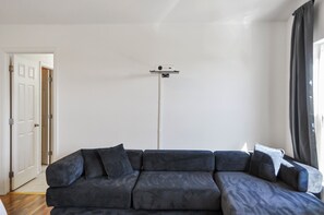 Ein modernes Wohnzimmer mit einem Ecksofa, einer installierten Überwachungskamera und einer Tür zu einem anderen Raum.