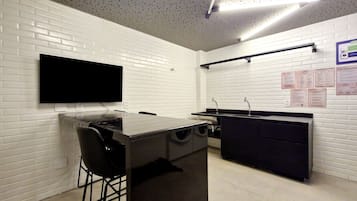 Una cocina moderna con paredes de ladrillo blanco, un televisor de pantalla plana sobre la encimera y una barra con taburetes.