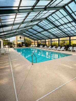 An indoor swimming pool with a glass ceiling, surrounded by lounge chairs. - The Heron Hideaway|Family Beach Retreat in Myrtle Beach (Myrtle Beach)