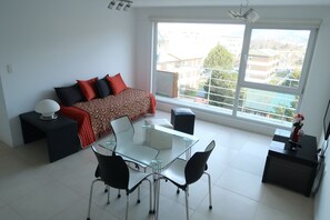 A modern living room with a sofa, a glass dining table, and chairs. - Josefina: Scenery and Tranquility (Ushuaia)