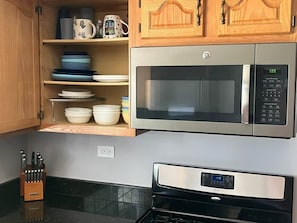 A kitchen with a stainless steel microwave oven, a built-in oven, and wooden cabinets above a countertop. - Lakehouse Getaway Plenty of Parking (Edgerton)