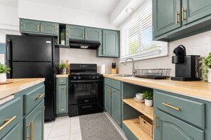 A modern kitchen with teal cabinetry, a black refrigerator, a stove, and a sink. - 714 Rockford apartment (Rockford)