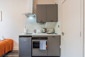 Ett kompakt pentry med inbyggd diskmaskin, mikrovågsugn och en liten ugn.