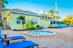 A pool area with lounge chairs, a small building, and a hot tub. - Tropical resort retreat near Disney (Davenport)
