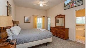 A bedroom with a bed, a dresser, a mirror, and a ceiling fan. - Tropical resort retreat near Disney (Davenport)