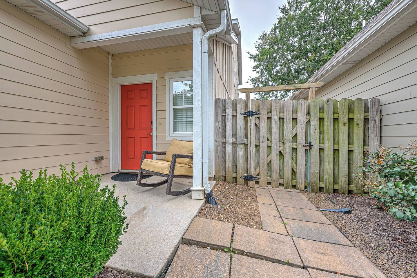 A house with a red door, a porch with a rocking chair, and a wooden fence.