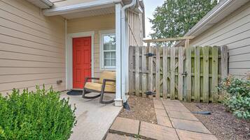 A house with a red door, a porch with a rocking chair, and a wooden fence.