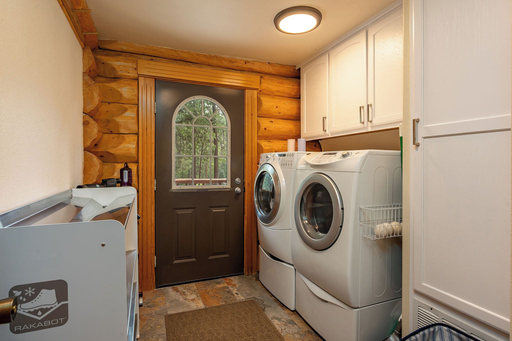 A compact laundry room with a wooden exterior, a large arched window, and a washing machine.