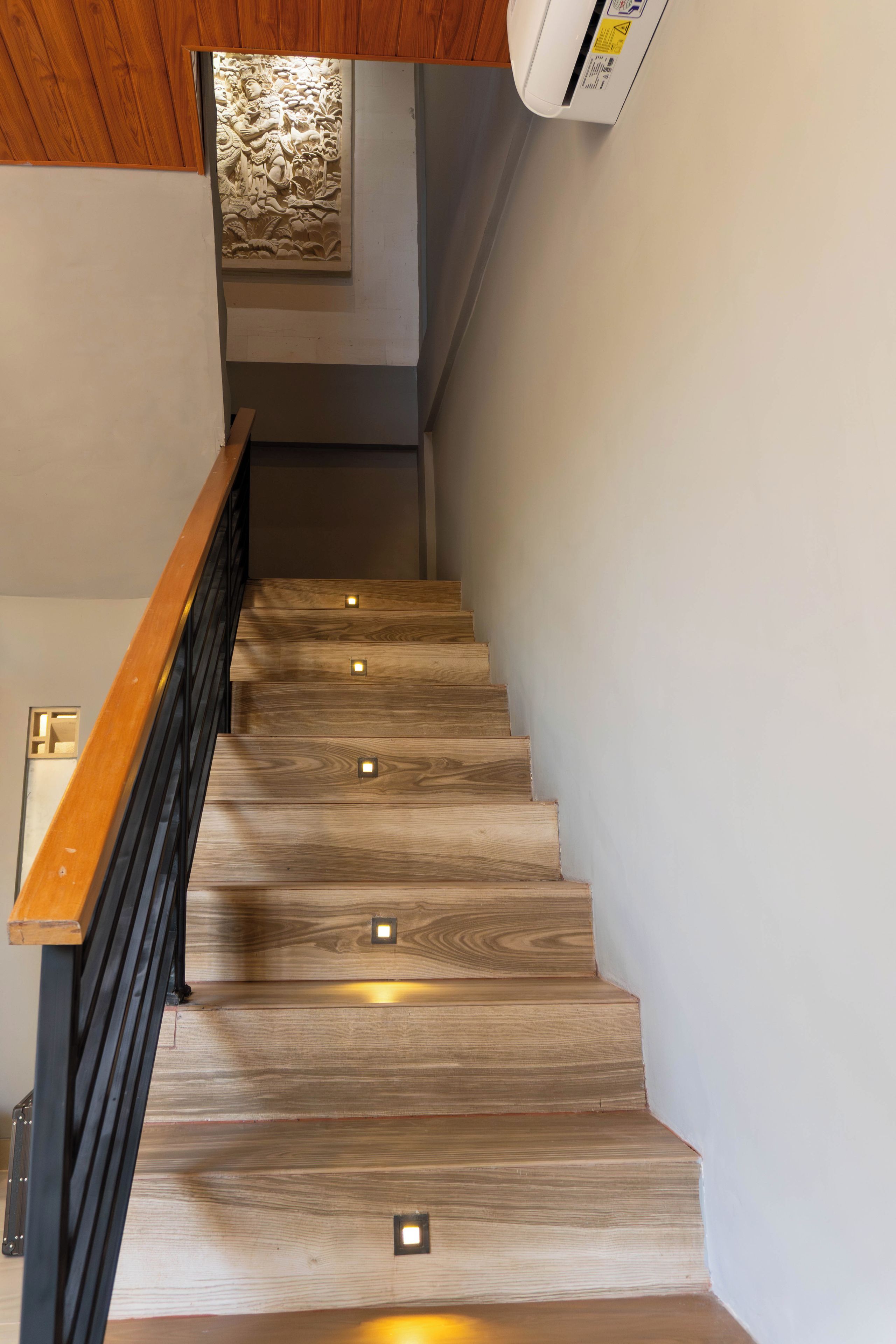 A wooden staircase with built-in lighting and a handrail.