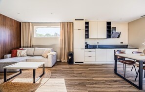 A modern living room with a sofa, a dining table, and a kitchen area with cabinets and a sink. - 2 bedroom luxurious home in Voorthuizen (Voorthuizen)