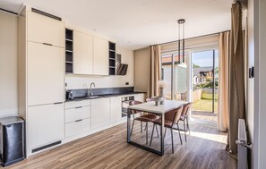 A modern kitchen with white cabinets, a black countertop, and a dining area with a table and chairs. - Beautiful home in Voorthuizen with WiFi (Voorthuizen)