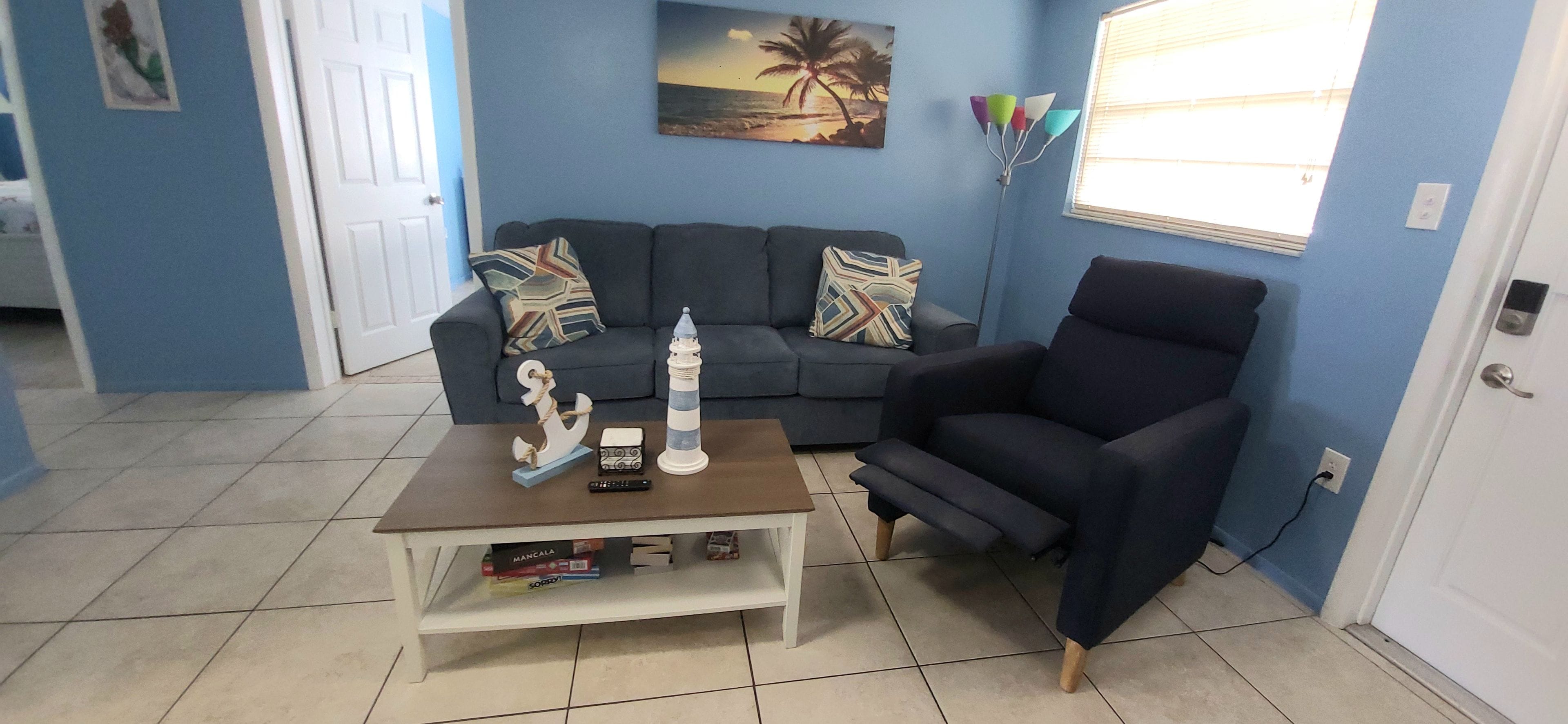 A living room with a sofa, armchair, coffee table, and decorative items.