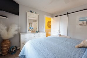 A bedroom with a bed, dresser, mirror, and a wall with a circular decoration. - Cozy Couples Getaway! Steps to the Beach & Ocean Annies! (Myrtle Beach)