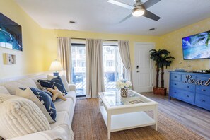 Un salon avec un canapé, une table basse et un téléviseur fixé au mur.