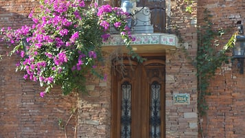 Un bâtiment en pierre avec une porte en bois et un balcon agrémenté de plantes en pot.