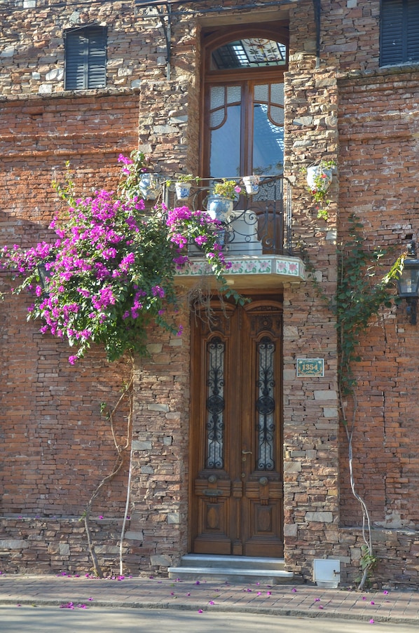 Un bâtiment en pierre avec une porte en bois et un balcon agrémenté de plantes en pot.