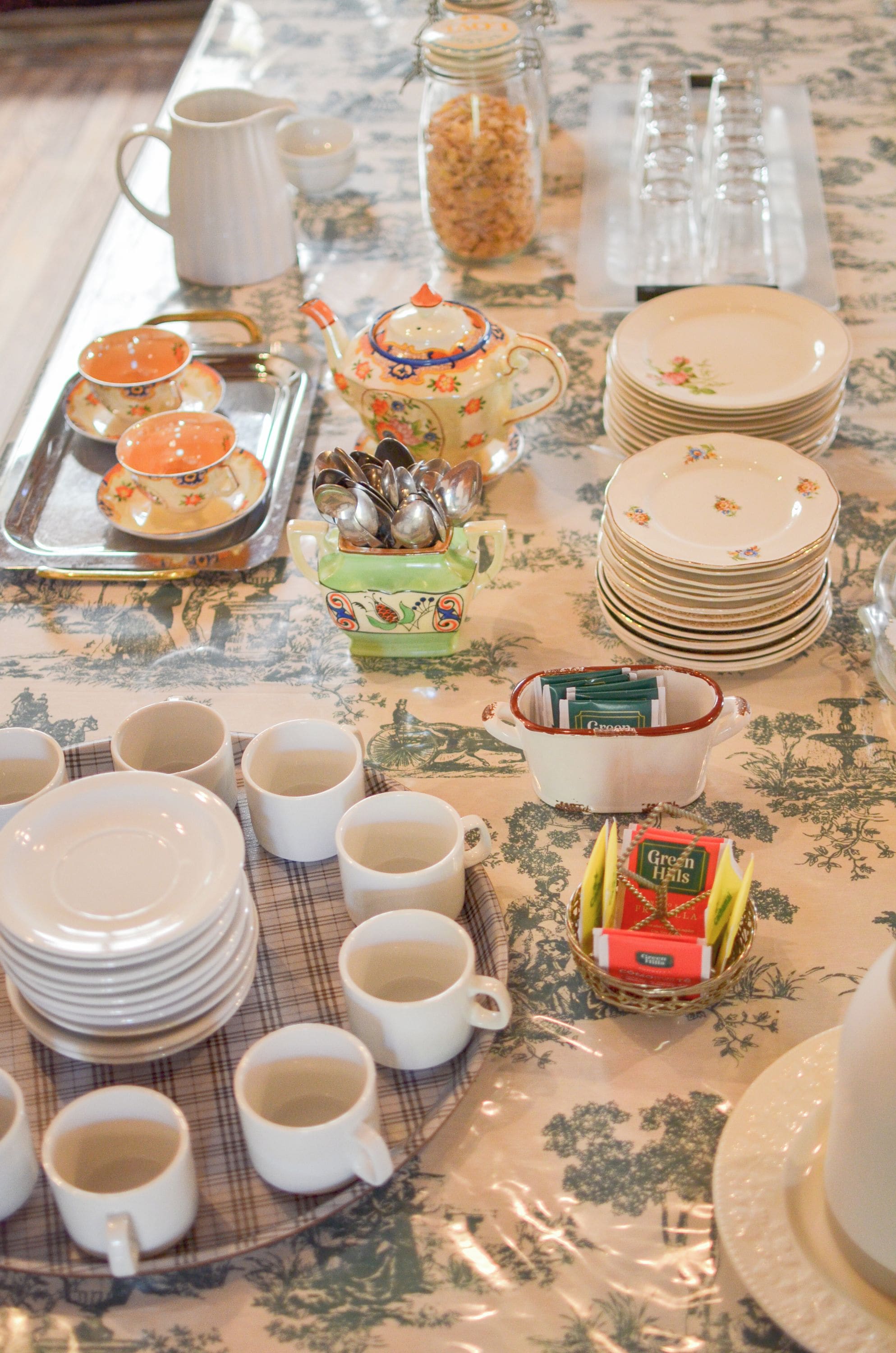 A table set with various dishes, cups, and a teapot, indicating a dining arrangement.