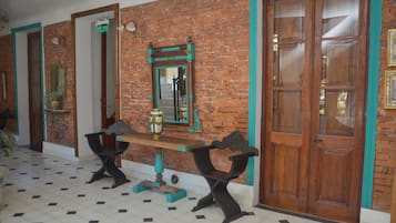Una habitación con pared de ladrillo, puerta de madera, espejo y una mesa con sillas.