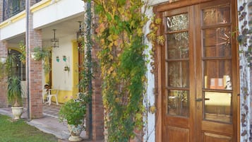 A building with a wooden door, a balcony with a railing, and a tiled entrance area.
