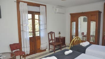 Une chambre d’hôtel avec deux lits, un bureau, une chaise, un miroir et une porte avec des rideaux.