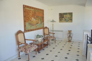 A room with a dining table, two chairs, a floor lamp, a vase, and two paintings on the wall. - Posada Los Angelos (Ramallo)
