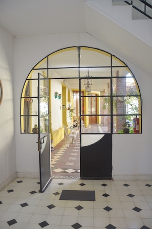 Une porte en arc donnant sur un espace repas, un sol carrelé et un luminaire suspendu.