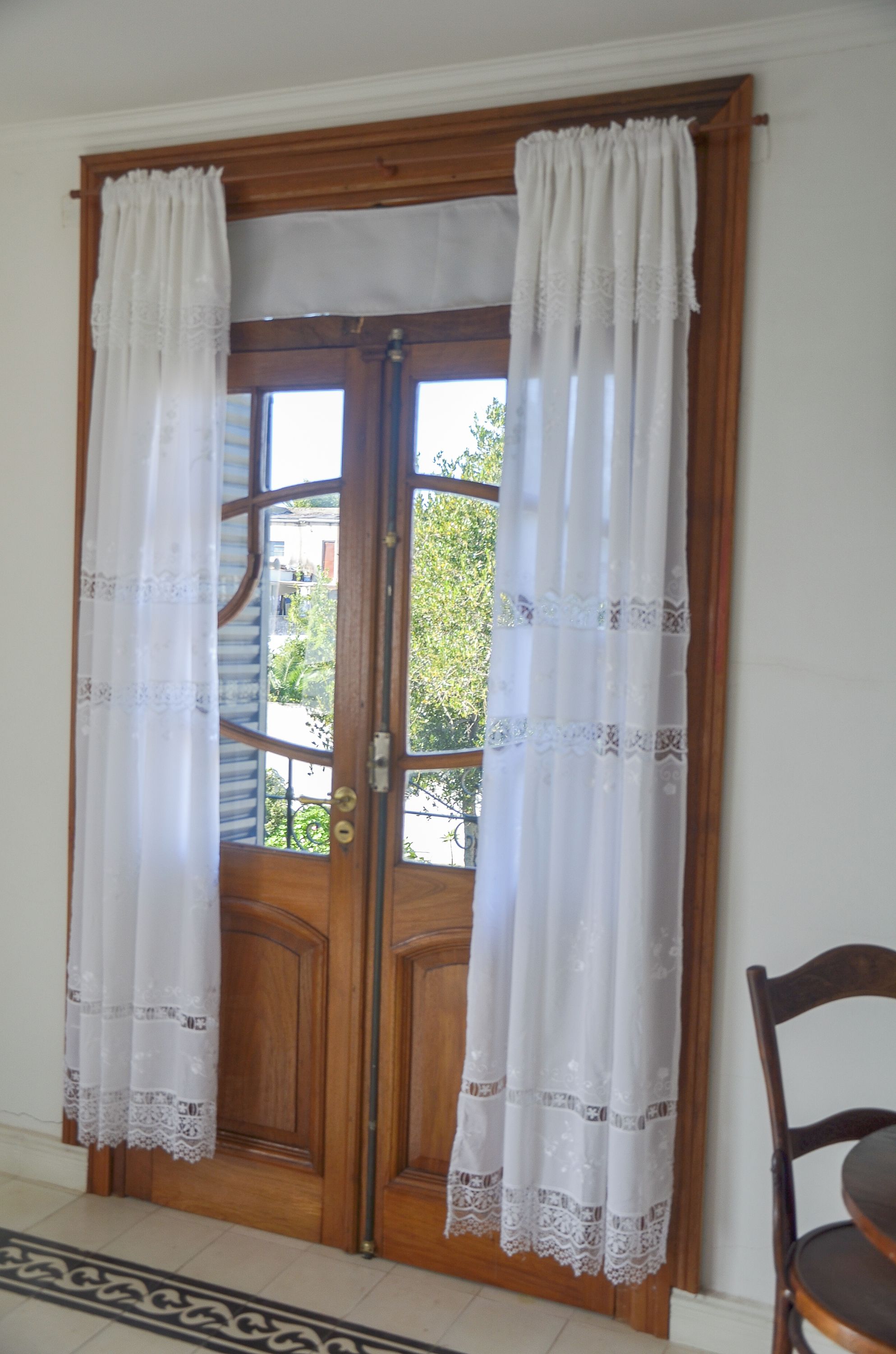 A wooden door with two glass panels, flanked by white curtains with lace trim.
