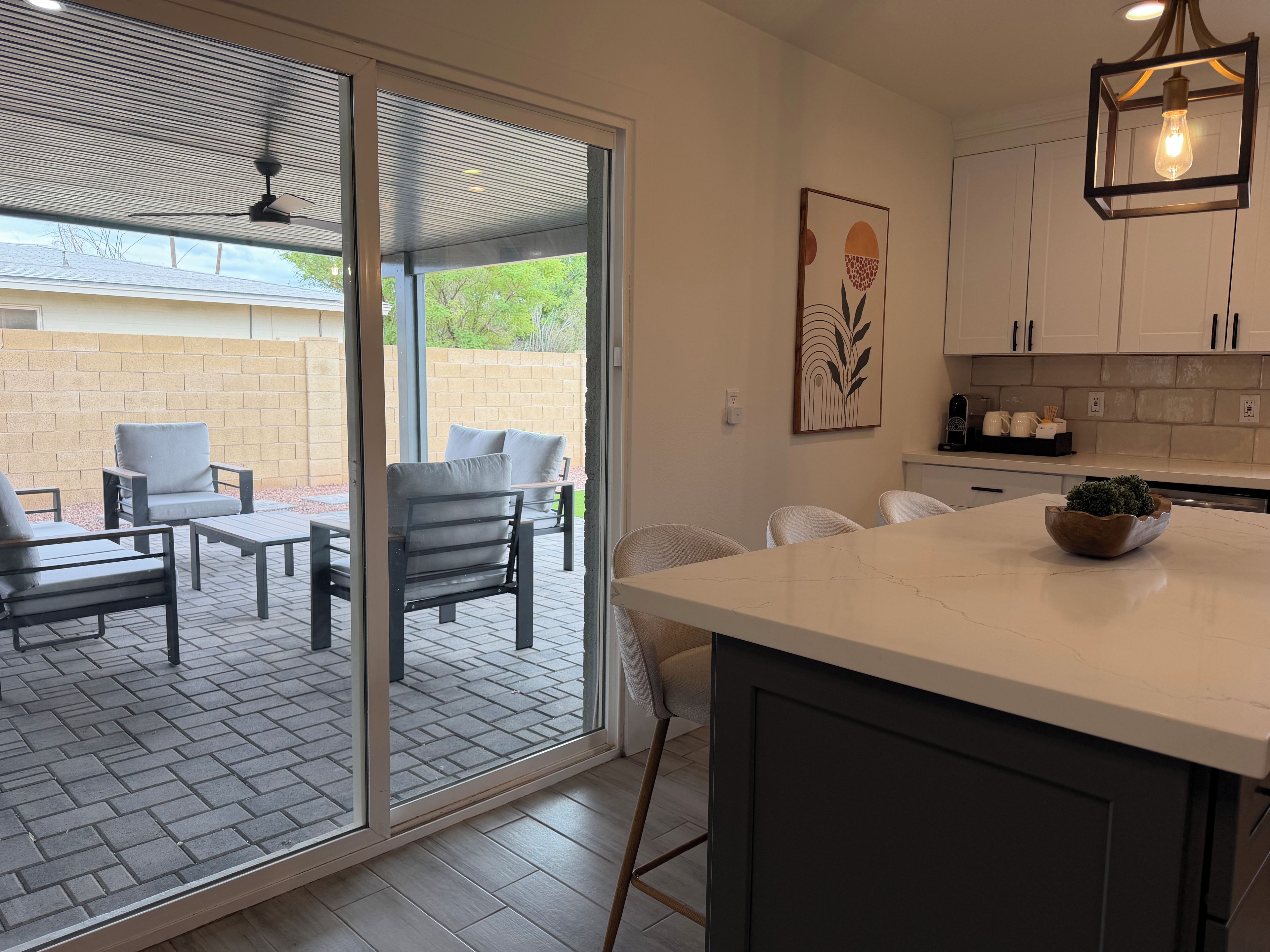 A modern kitchen with a marble countertop, a built-in island, and a dining area with outdoor seating.