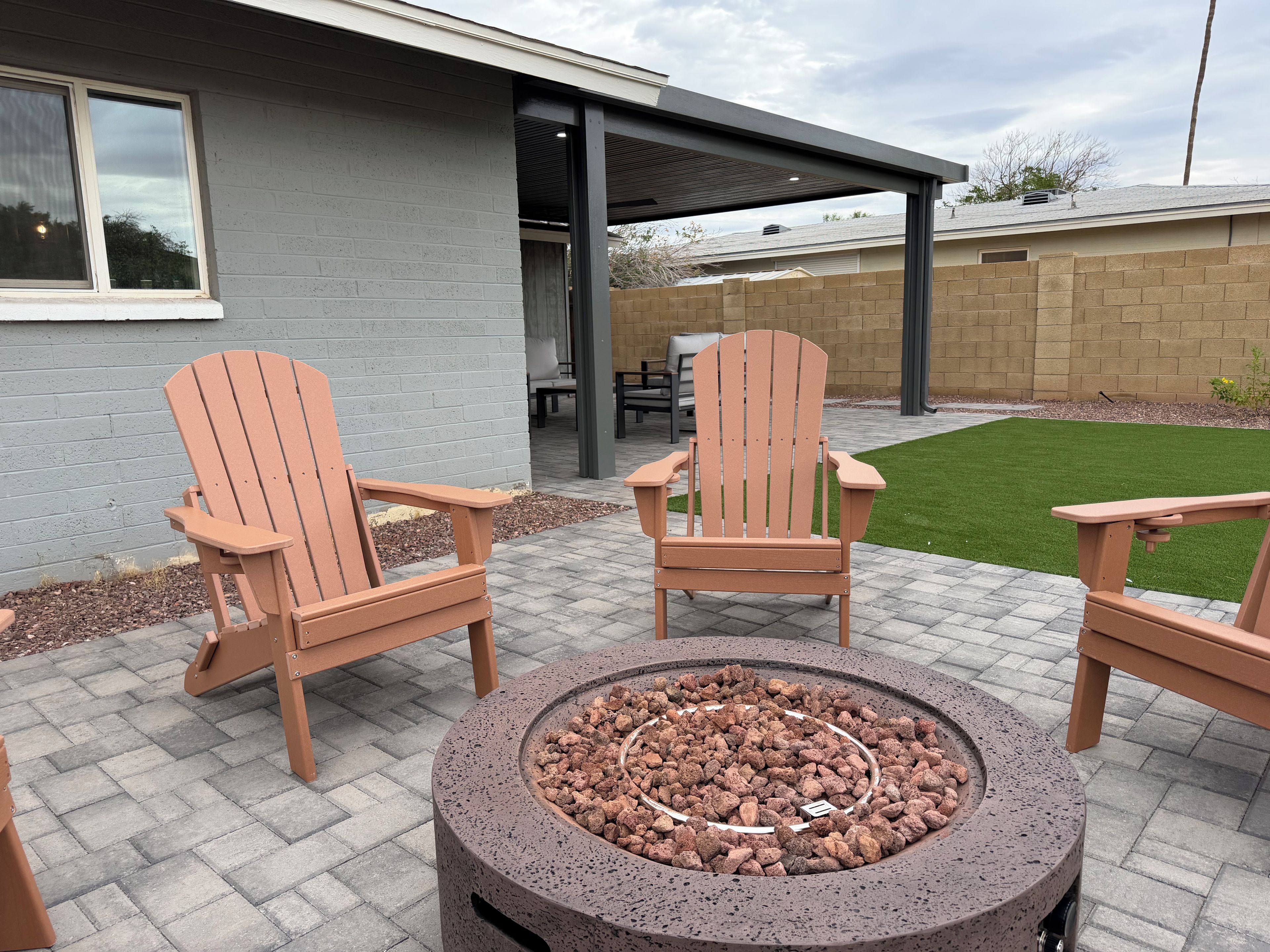 An outdoor seating area with Adirondack chairs and a circular fire pit.
