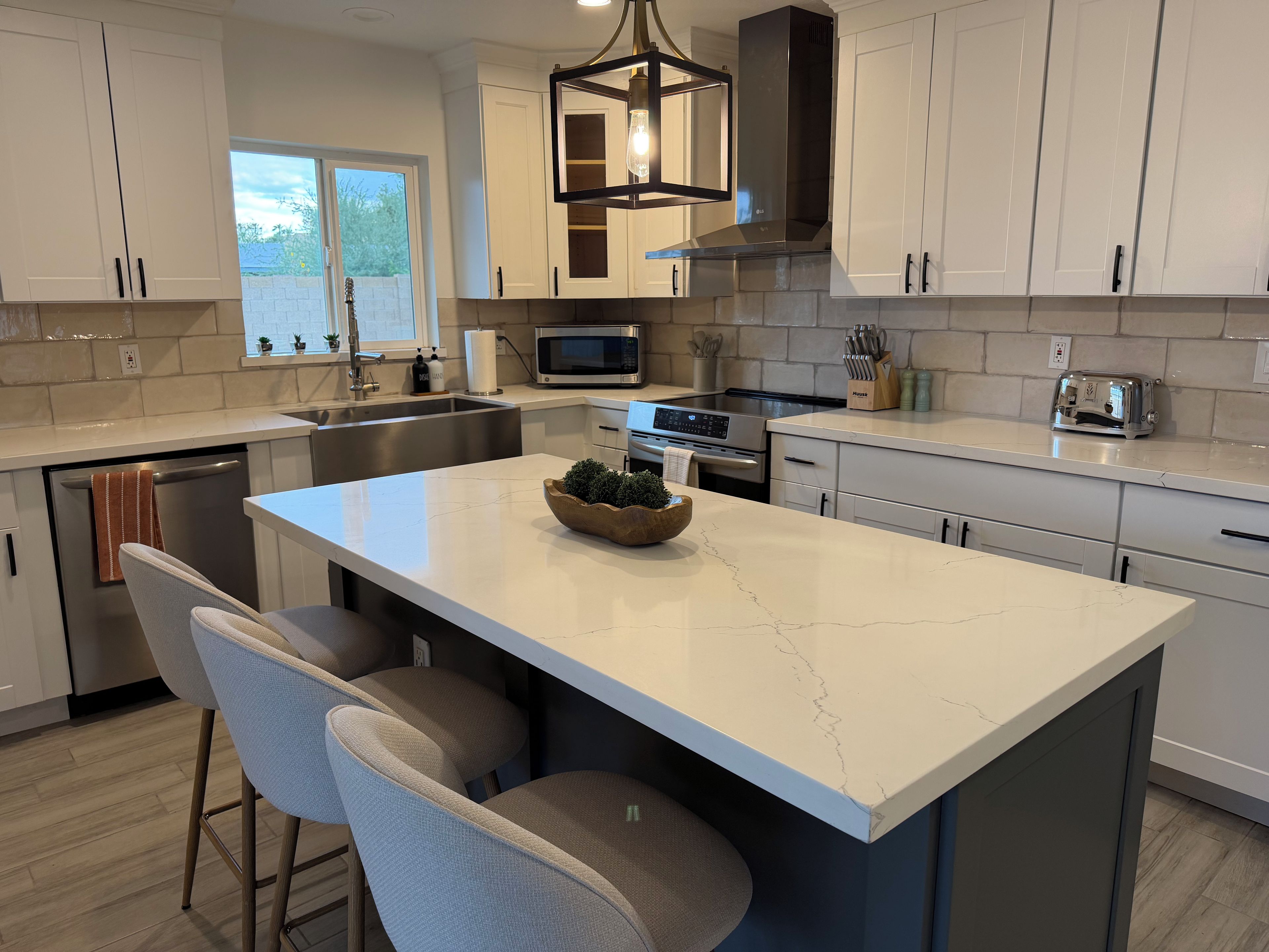 A modern kitchen with a central island, stainless steel appliances, and a window providing natural light.