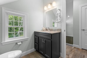 Un baño con ventana, un lavabo con espejo y un inodoro.