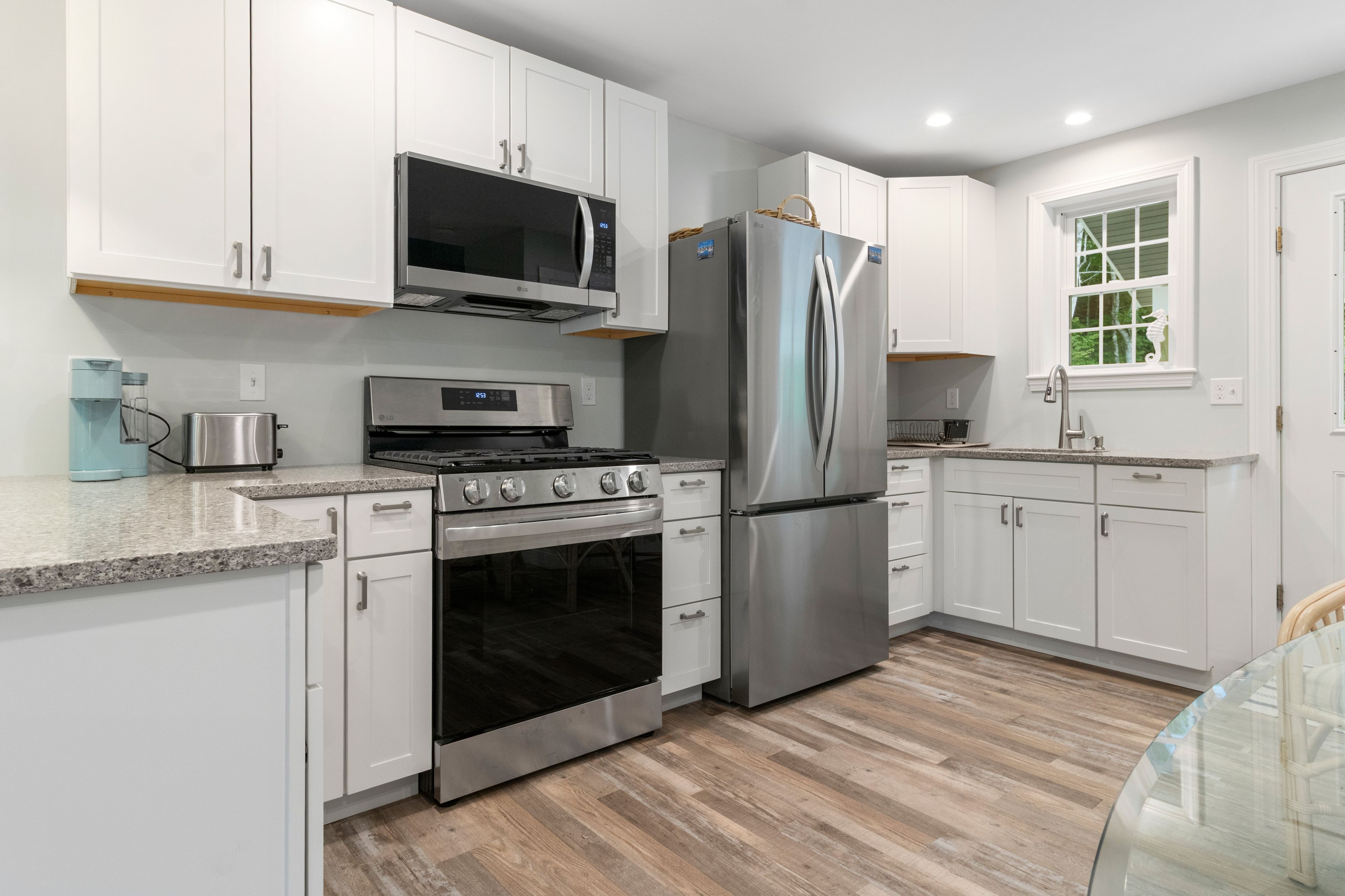 A modern kitchen with white cabinets, stainless steel appliances, a built-in oven, and a refrigerator.