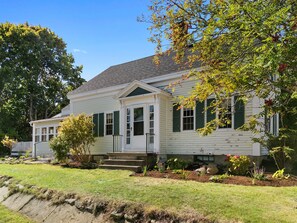 A two-story house with a front porch, a small garden, and a large tree. - Zlatibor (Camden)