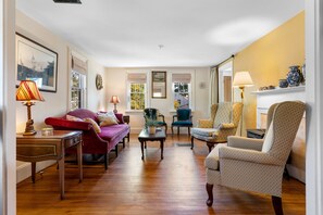 A spacious living room with hardwood flooring, a red sofa, a patterned armchair, and a green chair. - Zlatibor (Camden)