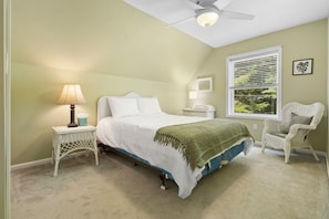 A bedroom with a bed, bedside table, lamp, chair, window, and ceiling fan. - Laurel Shores 3br/3ba Oceanfront Harpswell Retreat w/ Deck (Harpswell)
