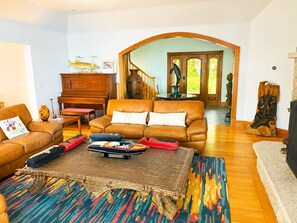 A spacious living room with a brown leather sofa, a patterned rug, and a wooden coffee table. - Private Oceanfront Retreat Panoramic Views, Deck & Rocky Shore (Brooklin)
