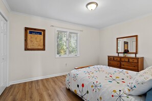 A bedroom with a bed, dresser, and a framed sign on the wall. - Twin Pines of Hendersonville (Hendersonville)