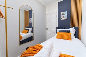 A hotel room with a bed, a mirror, a door, and a painting on the wall. - 4BR Wembley Stay w/ Pool Table & Free Parking (Greater London)