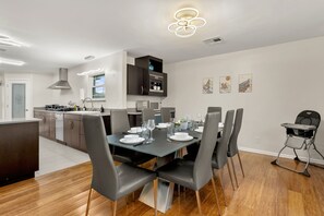 A modern kitchen with a dining area, featuring a central island, grey chairs, and a table set for six. - Private Pool & Loungers | Theater, Dry Sauna & Games (San Antonio)