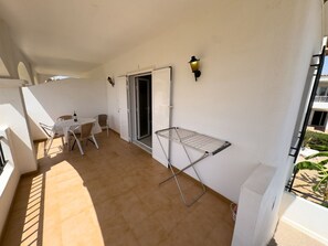 A balcony with a table and chairs, a drying rack, and a door leading to an interior space. - LLANOS 8 APARTMENT (Cuevas del Almanzora)