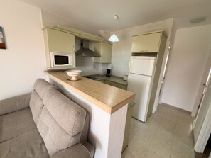 Cozinha compacta com micro-ondas, cafeteira e frigorífico.