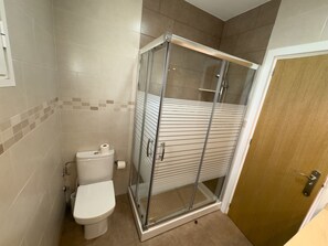 A bathroom with a toilet, a shower enclosure, and a wooden door. - LLANOS 6 APARTMENT (Cuevas del Almanzora)